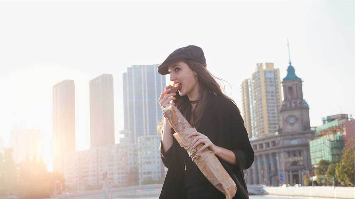 Female eating a baguette while walking.
